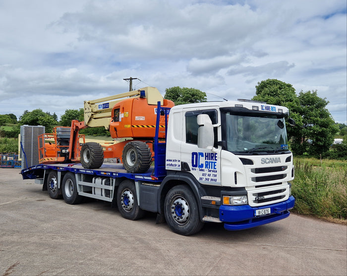 Truck with a crane on a road with trees and sky in the background